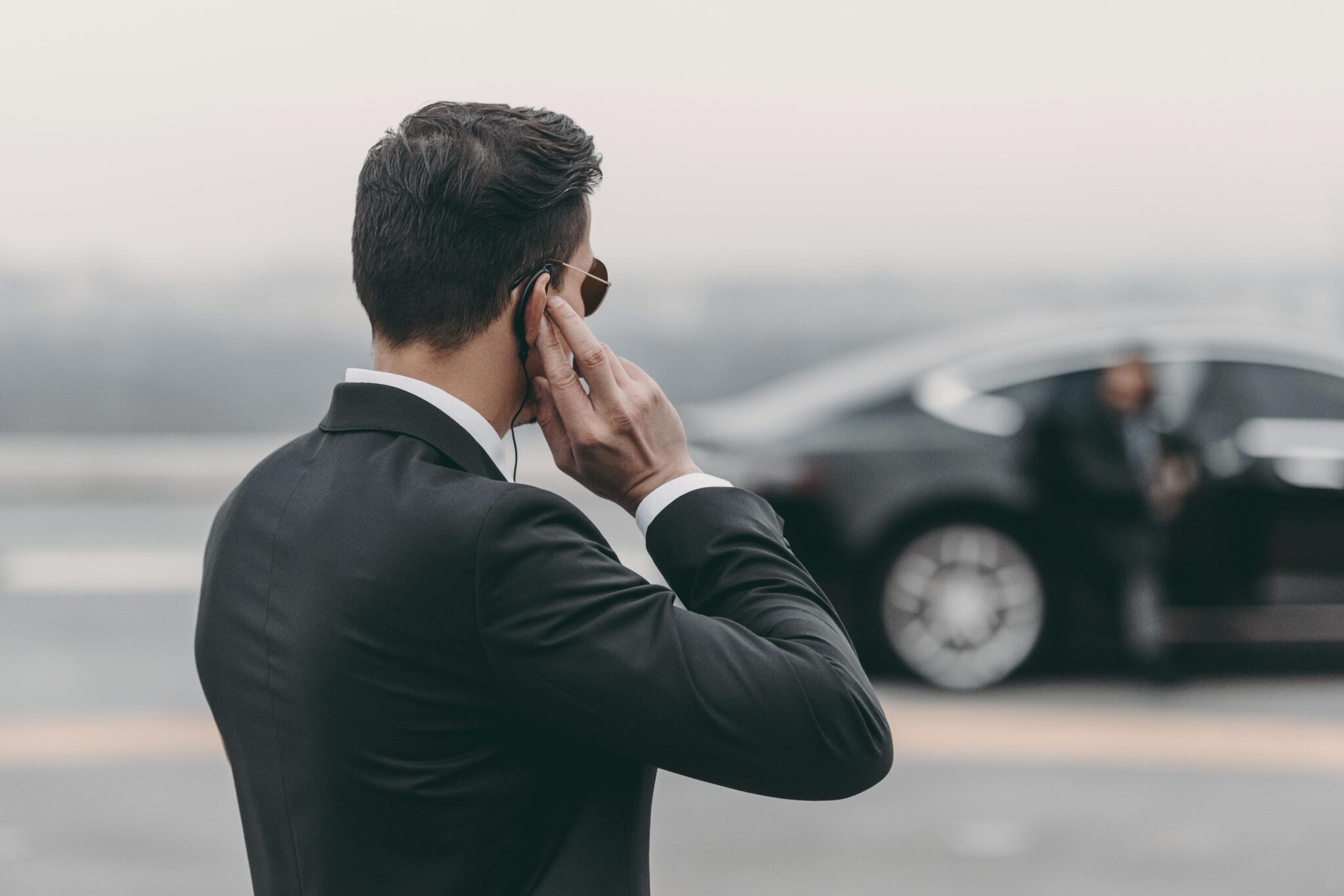 Man in suit with earpiece near car.