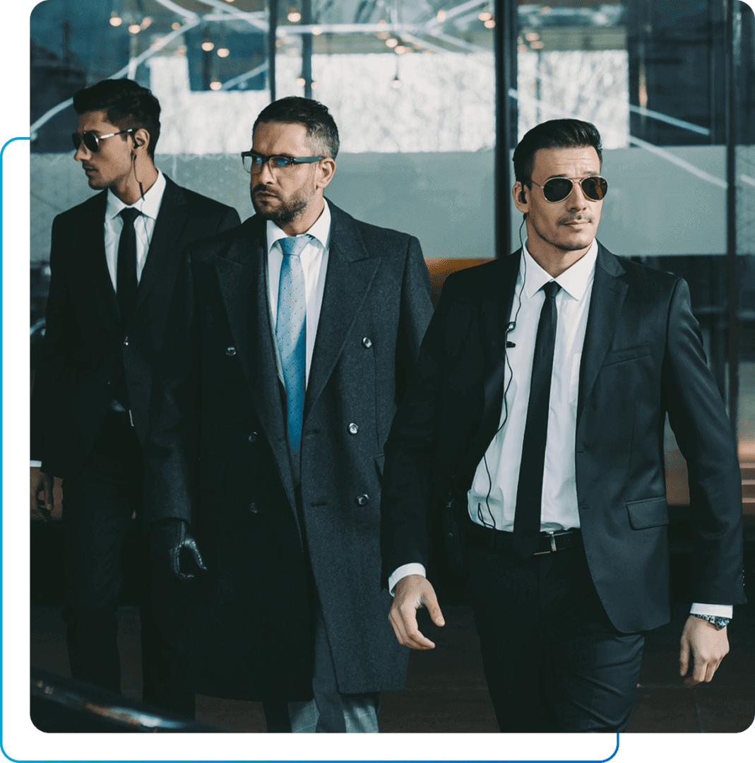 Three suited men with earpieces walking.