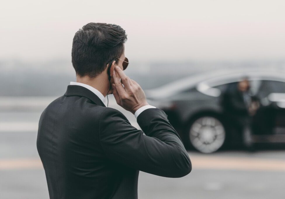 Man in suit with earpiece near car.